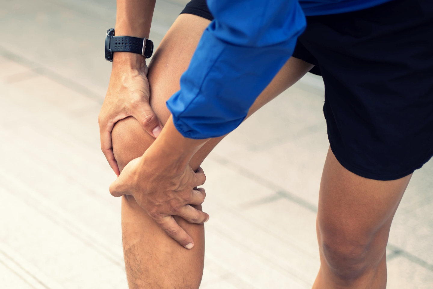 A man wearing a blue Windbreaker jacket., Knee pain after exercise concept.It happens often in athletes practice overtain.In arthritis concept.