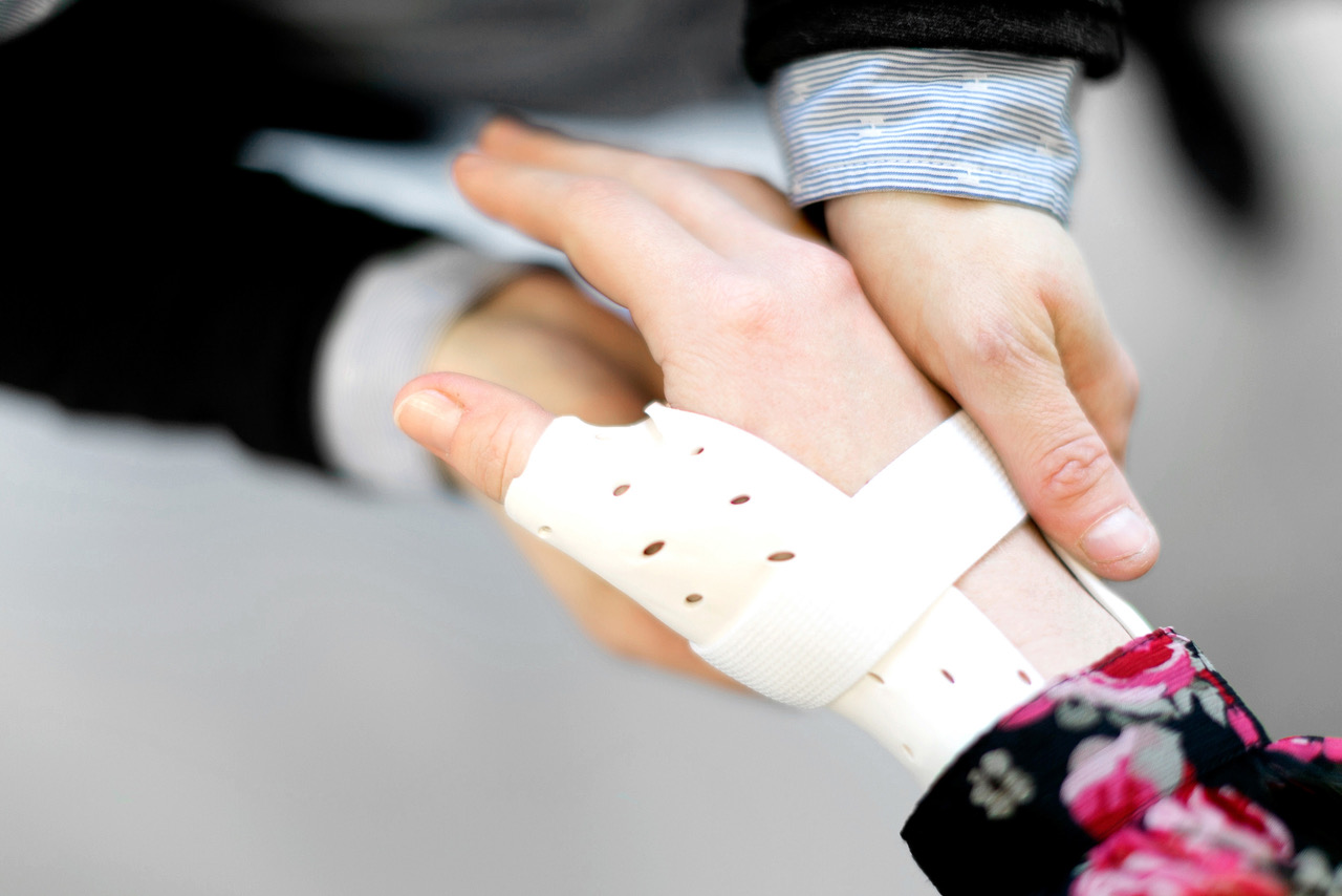 A close up of an orthotist fitting a patient with a thumb spica.