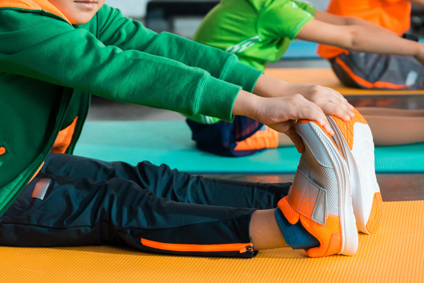 Selective focus of multiethnic kids stretching on fitness mats in sports center