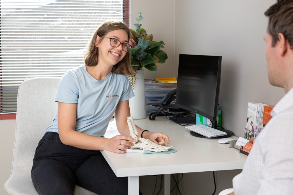 Smiling patient in a consultation with an Orthotics Plus clinician