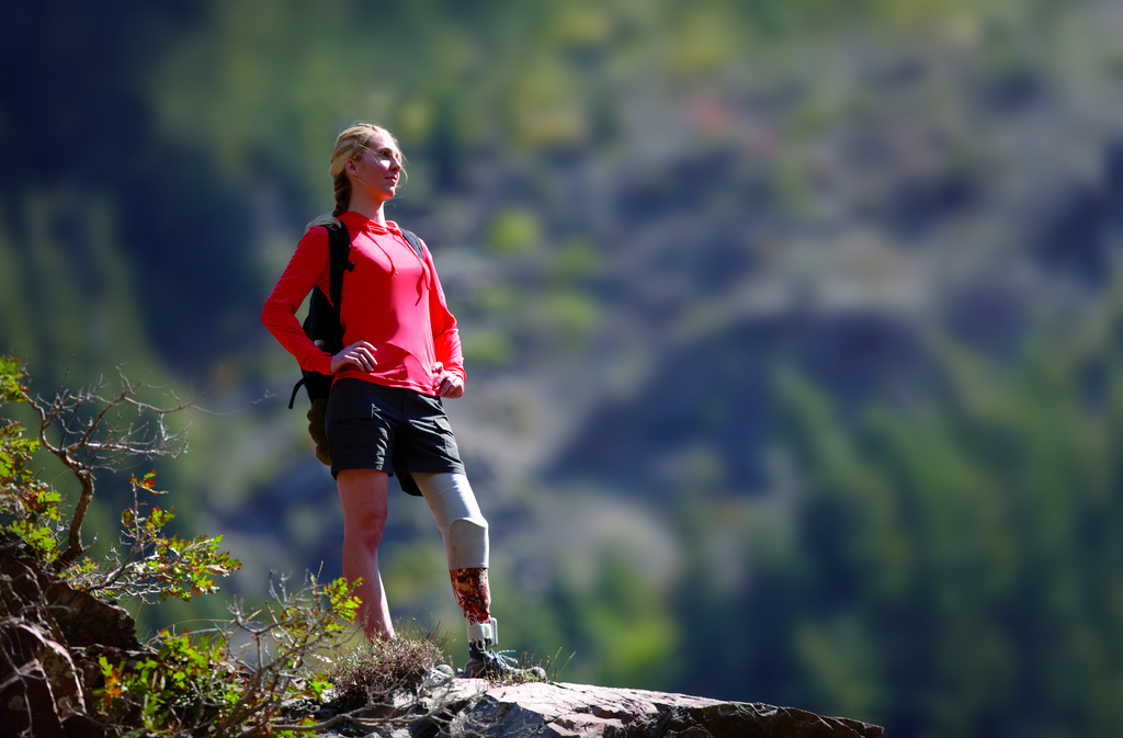 Woman with a below knee prosthetic leg standing on a hiking trail