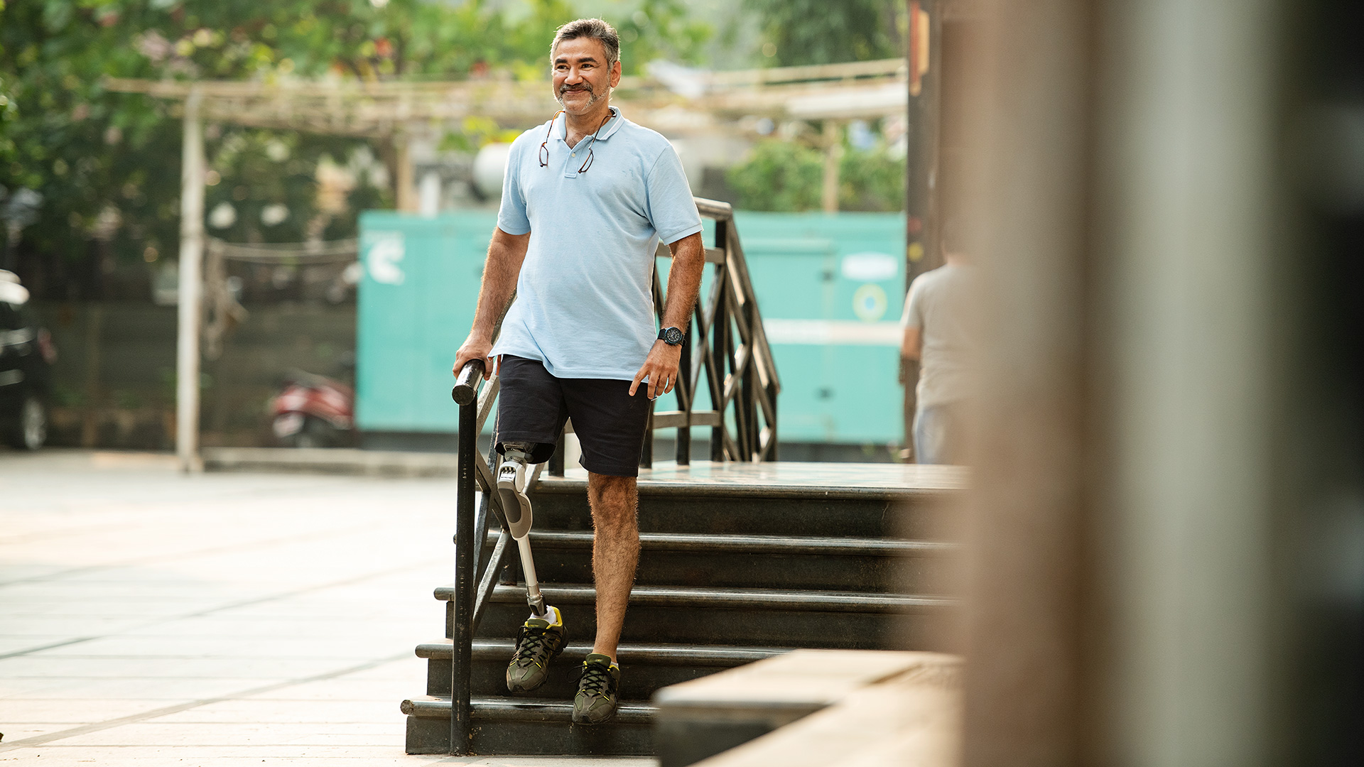 Man walking down outdoor steps with an above knee prosthetic leg